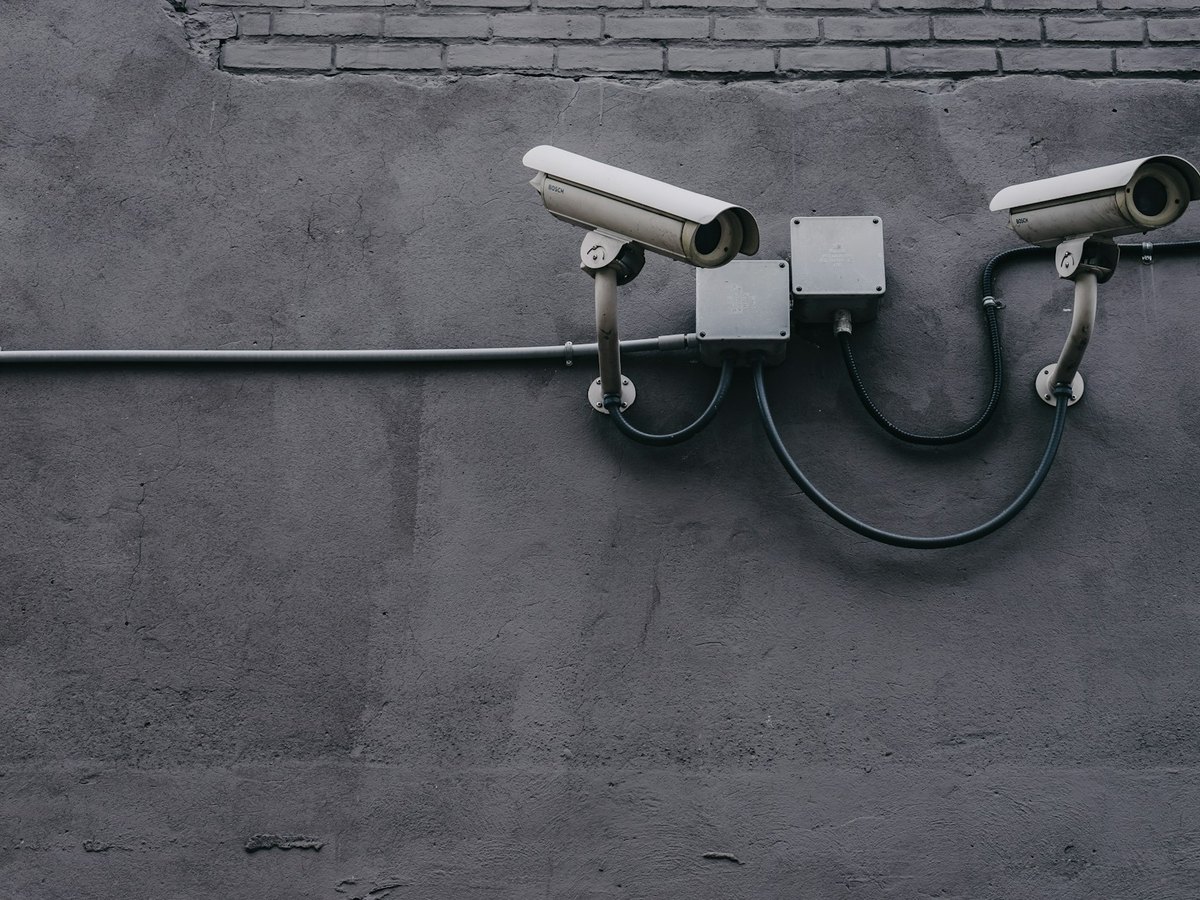 Two outdoor surveillance cameras mounted on a concrete wall